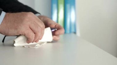 Ofisteki işadamı gözlüğünü beyaz temiz bir bezle siliyor.