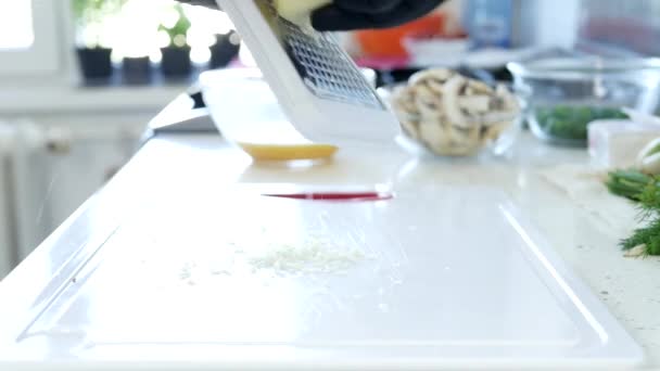Ο άνθρωπος στην κουζίνα τριμμένο αρωματικό λευκό τυρί για ένα μαγειρικό πιάτο — Αρχείο Βίντεο