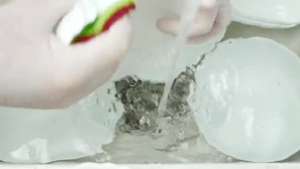 As mãos da governanta vestindo luvas de proteção Lave os pratos no dissipador usando água e esponja de lavar louça — Vídeo de Stock