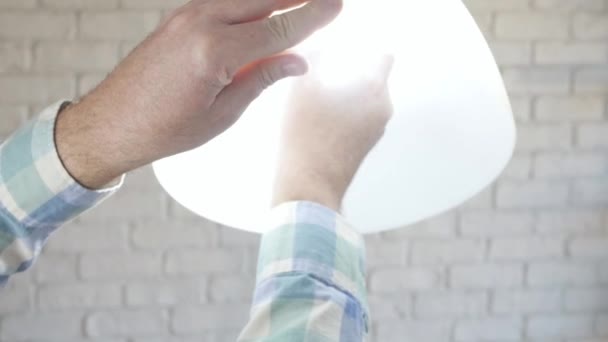 El hombre desenrosca cambiar una bombilla led en una lámpara. La iluminación moderna con tecnología led ahorra energía en el hogar. — Vídeo de stock