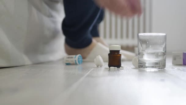 Idős személy veszi papucs a láb és néhány orvosi tabletták a padlóról, közel az ágyhoz. — Stock videók