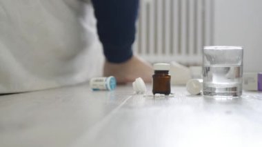 Yaşlı adam ayaklarından terlik ve yatağın yakınındaki yerden bazı tıbbi haplar alıyor..