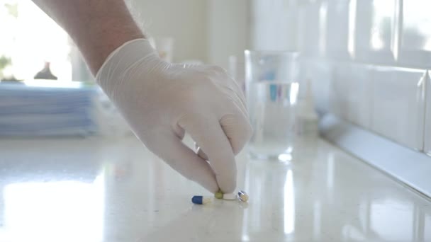 Läkare bär skyddshandskar i händerna Presentera en medicinsk piller. — Stockvideo