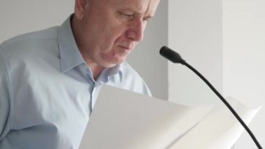 Gazetelerden okuyan ve basın konferansında konuşan iş adamı. Basın röportajında konuşan adam..