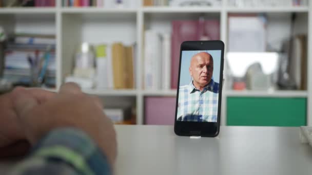 Ένα πρόσωπο στο σπίτι με ένα κινητό τηλέφωνο συνομιλίες σε απευθείας σύνδεση με ένα φίλο από διακοπές Χρησιμοποιώντας μια εφαρμογή Video Conference. — Αρχείο Βίντεο