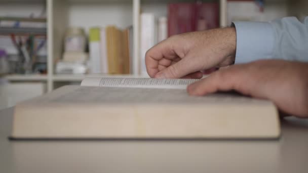 Un uomo in biblioteca che legge un libro di letteratura. Studente Studiare un dizionario a casa. — Video Stock