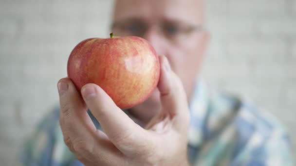 Hongerige man met een verse rode appel in zijn hand. Lekker en zoet fruit voor een dessert. — Stockvideo