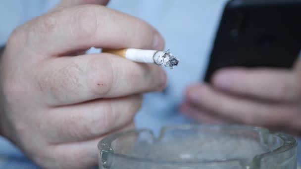 Raucher, der gleichzeitig mit dem Handy eine Zigarette raucht. Entspannter Geschäftsmann Rauchen und Surfen im Handy-Internet. — Stockvideo