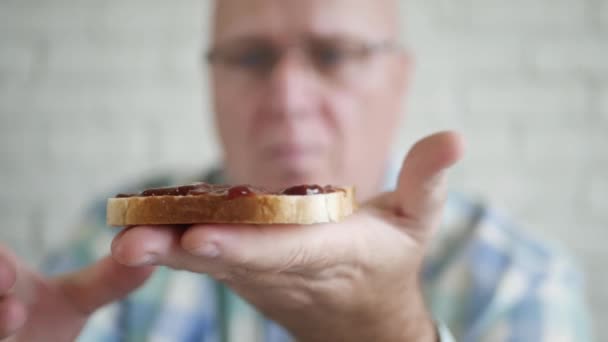 Uitgehongerde persoon Eet een heerlijke toast met aardbeienjam bij het ontbijt. hebzuchtige en hongerige man eten van een zoete snack. — Stockvideo