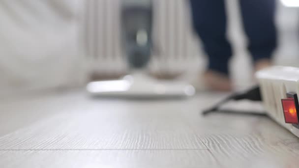 Tiro desfocado com um homem usando um aspirador de pó em casa em atividades domésticas, limpando o chão do escritório com aspirador de pó. — Vídeo de Stock