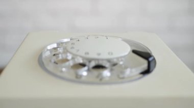 Adam Telefon Kullanıyor, Diski Döndürüyor ve Telefon Numarasını Çeviriyor. Kablolu iletişim için kullanılan eski sabit hat teknolojisi.