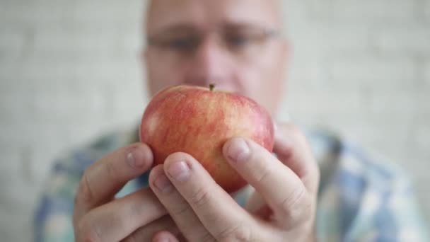 Svältande person som ser girig ut till ett fräscht och aptitretande rött äpple till frukost. Hungrig man förbereder sig för att äta ett äpple. — Stockvideo