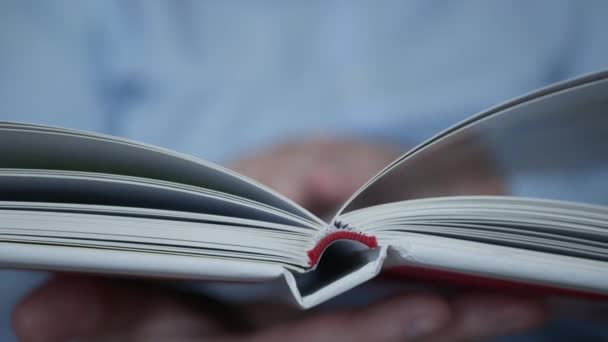 Τα χέρια γυρίζουν τις σελίδες ενός βιβλίου. Ανάγνωση ενός ατόμου, και μάθηση από ένα βιβλίο σε μια βιβλιοθήκη. — Αρχείο Βίντεο