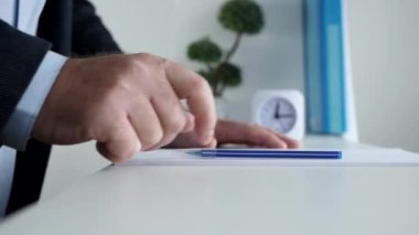 Ofisteki sıkılmış iş adamı elinde kalemle gergin hareketler yapıyor..
