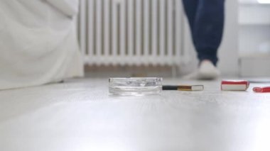 Son sınıf öğrencisi terliklerini giyer, yatak odasında yürür, bir sigara içer ve yerden direkt olarak alkolle bir bardak içer..