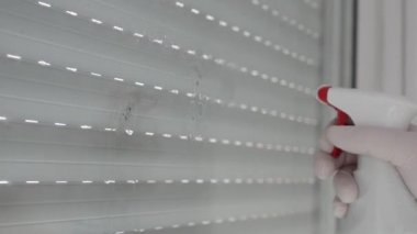 Eldivenle korunan, cam yüzeyini temizleyen, dezenfektan ve temiz mendil kullanan eller..