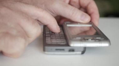 Detacable tuş takımı olan eski bir cep telefonunu kullanan bir kişi. Eski Teknoloji Cep Telefonu Kullanan Adam Metni.