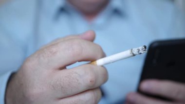 İş Adamı Sigara İçiyor, Cep Telefonu Kullanarak Mesaj Yazıyor. Rahatlamış Kişi Cep Telefonu ve Sigara Kullanıyor