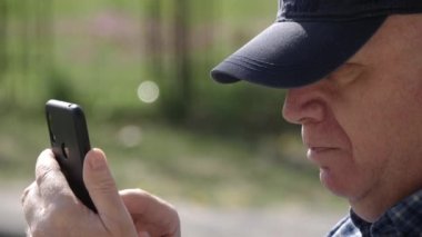 Sıkıcı ve üzgün kişi cep telefonundan mesaj yolluyor ve okuyor. Cep Telefonu Bağlantısını Kullanan Adam Metni.