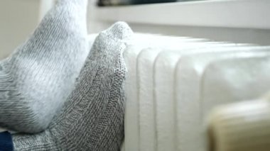 Evde Hasta Bir Kişi Oturup Kaloriferde Ayaklarını Isıtıyor.