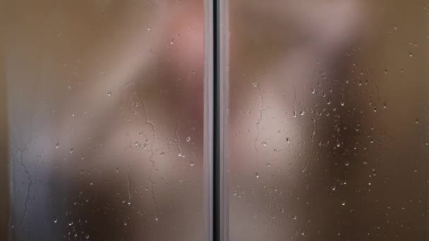 Размытое изображение с человеком в ванной комнате, душ за кабиной Прозрачные двери, очистка его тела с горячей водой и шампунем. — стоковое видео