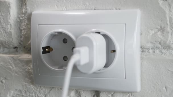Desligar um carregador de telemóvel de uma tomada de parede eléctrica. Desconectar um carregador de telefone da tensão de energia. — Vídeo de Stock
