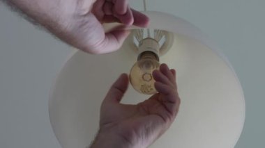 Elektrikçinin Eli Odadaki Işığı Açar, Soketi vidalarken Sıcak Işıklı Yanan Ampul.