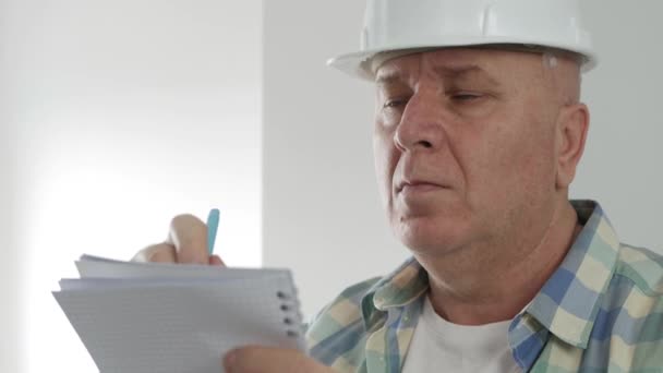 Skjuta med en konstruktör tar anteckningar i Agenda. Arbetstagare i byggnadsindustrin Utarbetande av en arbetsplan för grönboken. — Stockvideo