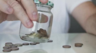 Piggy Bank kavanozunu bozukluklarla kontrol eden yaşlı bir adam. Domuzcuk Kumbarasında Çeşitli Paralarla Yapılan Tasarruflar.