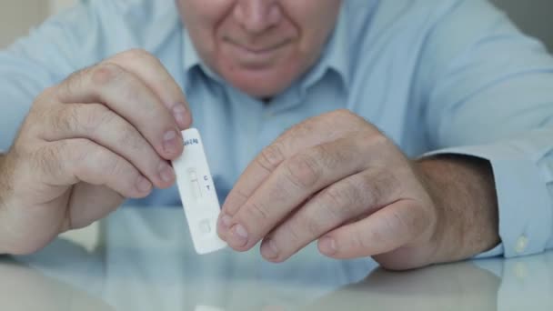 Test Sars Cov 2 négatif maintenu en main par une personne hospitalisée. Tir avec une personne âgée regardant vers un test rapide de coronavirus. — Video