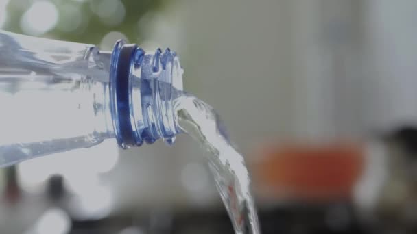 Durstige Person gießt klares Wasser aus einer Plastikflasche. Kaltes und frisches Wasser fließt aus einer Plastikflasche, die ein Glas füllt. — Stockvideo