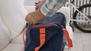 Fermuarı kapatan, spor çantasını alan ve odayı terk eden adam..