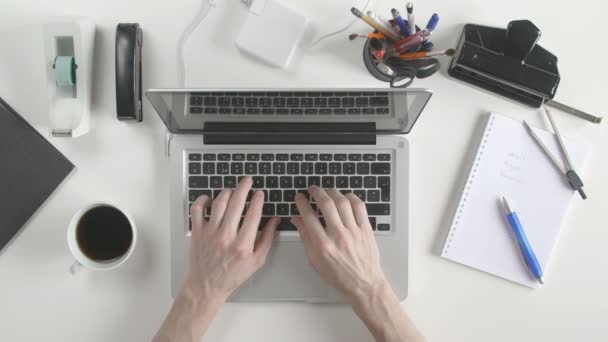Oversikten over skrivebordet. En mann som skriver på laptopen sin . – stockvideo