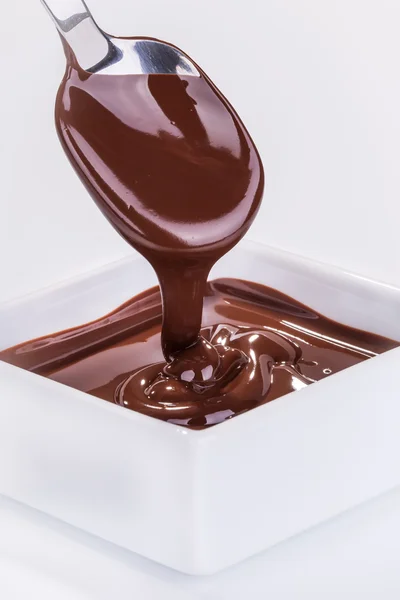 La salsa di cioccolato scorre giù da un cucchiaio — Foto Stock