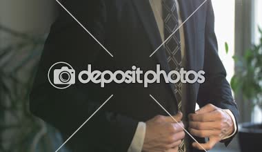 Beyaz gömlekli bir iş adamı ceketini ilikliyor.