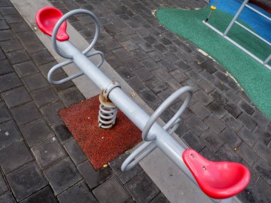 Bahçede demirden yapılmış, kırmızı sandalyeli bir testere..