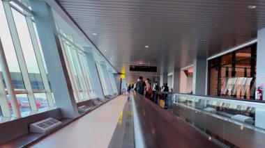 Modern Havaalanı Terminali. Hareket halindeki turistler, geniş pencerelerden gelen doğal ışıkla aydınlatılıyor. Yolcuyu yönlendirmek için kafanın üstündeki işaret. Tangerang, Endonezya, 11 Haziran 2025