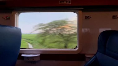 Tren penceresinden bak. Şehirlerarası bir trenin penceresinden güzel bir manzara, yeşil pirinç tarlaları ve kenarlar boyunca uzanan yerleşim alanları..