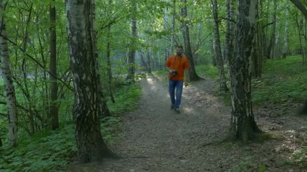 Hombre fotógrafo toma fotos al aire libre en el bosque — Vídeo de stock