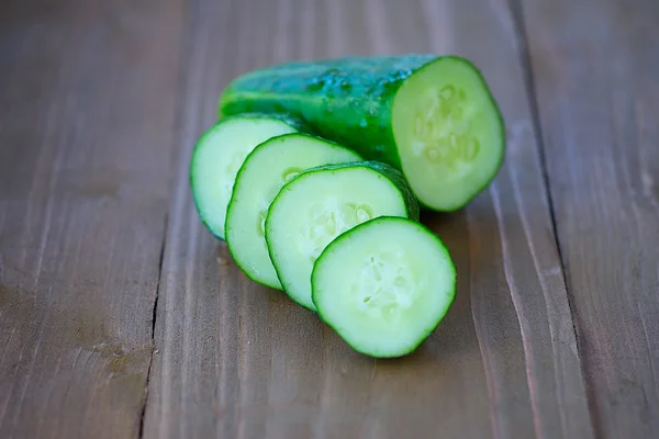 Cucumber slices on wooden background — Stock Photo, Image