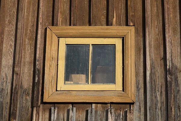 Een klein venster op de muur van de oude rustieke huis — Stockfoto