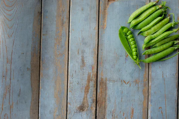 Groene erwten in peul vers geplukt op rustieke houten tafel — Stockfoto