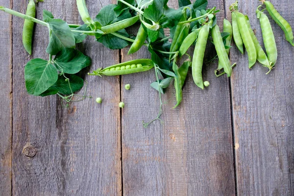 Green peas in pods freshly picked on wood background — Stock Photo, Image