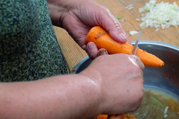 Woman hand cutting raw fresh carrot — Stock Photo, Image