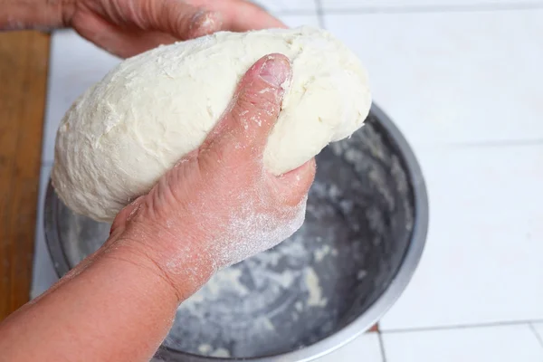 Les mains de la femme pétrissent la pâte sur un bol en métal — Photo