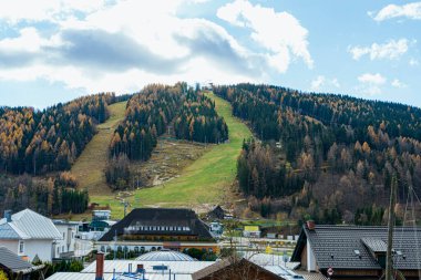 Mountain village with ski slopes and autumn forest landscape.