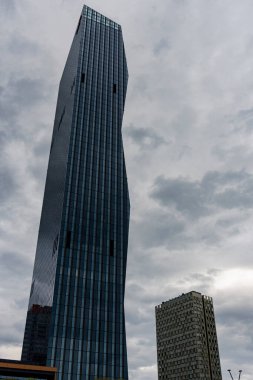 Avusturya, Viyana 'da bulutlu bir gökyüzüne karşı açısal tasarımı olan modern cam gökdelen. Çağdaş mimari ve kentsel ufuk çizgisi kavramı.