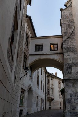 Gökyüzü açıkken, eski taş binalar arasında kemerli geçidi olan tarihi Avrupa sokağı..