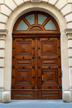 Zarif ahşap çift kapılı süslü paneller ve kemerli bir pencere klasik bir taş cepheye yerleştirilip rafine edilmiş mimari ve tarihi bir atmosfer yaratır..