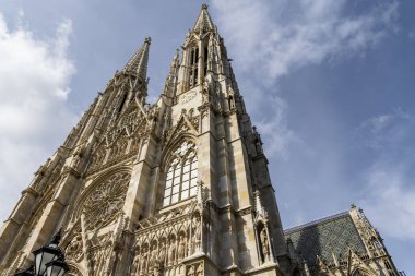 Mavi gökyüzüne karşı ikiz kuleleri ve süslü taş cepheleri olan Gotik bir katedralin alçak açılı görüntüsü. Dramatik, zamansız mimari seyahat, din, kültür ve Avrupa mirası kavramları için ideal.